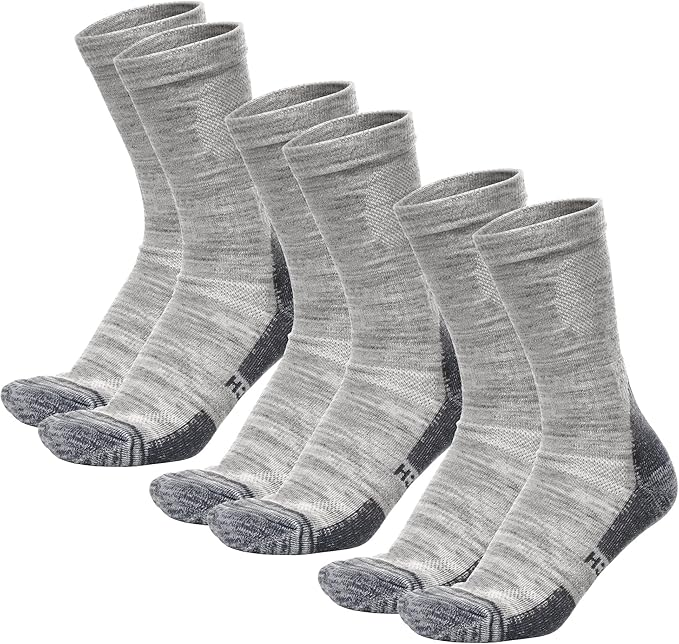 Thick merino wool camping socks folded neatly on a rustic table, perfect for staying warm during cold weather camping and winter adventures.